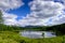 Mountain landscape, white clouds, lake and mountain range in the distance. Fantastic sunny day in mountains, large panorama