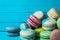 Mountain of macaroons on a turquoise wooden background, a French almond cookie lies on a close-up table. Copy space