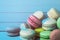 Mountain of multicolored macaroons on a turquoise wooden background, a French almond cookie lies on a close-up table