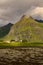 Mountain over traditional Norwegian house in cloudy weather, Lofoten islands, Norway