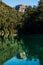 Mountain peak and forest with a calm turquoise lake reflecting. Arrayanes River, Los Alerces National Park. Vertical