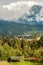 Mountain peak with sun that passes through the clouds. Wooden shelters in the foreground