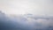 Mountain peak with a TV/radio relay on top, as seen above the clouds, on a cloudy Winter day with atmospheric inversion