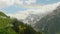 Mountain peaks covered with snow woth thick fluffy clouds and a rainbow above them. Nice view of russian nature.