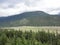 Mountain Range with Forests and Stream. Lush temperate rainforest in alaska with clouds and sun