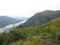 Mountain Range with Forests and Stream. Lush temperate rainforest in alaska with clouds and sun