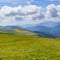 Mountain range with green meadows, flowers and blue sky with big white clouds. Relaxing and peaceful nature scene. Spanish