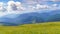 Mountain range with green meadows, flowers and blue sky with big white clouds. Relaxing and peaceful nature scene. Spanish