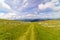 Mountain range with green meadows, flowers and blue sky with big white clouds. Relaxing and peaceful nature scene. Spanish