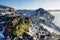 Mountain range with a green texture covered of snow above the frozen lake