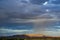 Mountain ranges, valley town under thick bank of rain clouds raining down