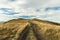 Mountain ridge highland dry grass meadow dirt trail route to horizon board scenic landscape autumn background view, copy space