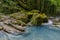 Mountain river in the gorge and stones covered with moss. Waterfall and dense vegetation.