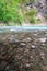 The mountain river Khosta with boulders, stones and pebbles on its sides in springtime. Clear green water of the burly creek in