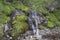 Mountain river with a little waterfall with moss and grass