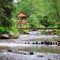 Mountain river, lush vegetation and recreation area with a bridge and gazebo. Location place Carpathian, Ukraine, Europe. Concept