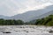 Mountain river with rapids and rifts, slopes with coniferous trees, bubbling stream of water