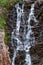 Mountain rivulet flowing from a lake by a waterfall along the steep, rocky slopes of the coast in the Barents Sea beyond the