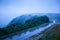 Mountain road in foggy dusk, motorcycle riding on asphalt road through the mountain top of Phnom Bokor Mountain in rainy day,