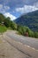 Mountain road landscape Swiss Alps mountains cyclists bicycle blue sky white clouds green forest trees summer travel highway rural