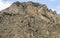 Mountain rock high stone wall windblown group of cobblestones at the foot of a steep climb dangerous walk