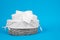 Mountain of rolls of extra soft toilet paper in wicker basket with fabric cover on blue background, front view, copy space