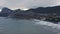 Mountain and sea bay landscape from drone in resort city. Mountain range over Sudak, sea waves splashing on beach