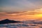 Mountain silhouette above the clouds at sunrise, view from the top view of mountains.