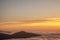 Mountain silhouette above the clouds at sunrise, view from the top view of mountains.