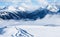 Mountain ski resort. Snowcat trail on snow slope. Snowy mountains. Ski resort landscape on clear sunny day. Panoramic