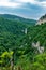 Mountain with a steep rocky slope and valley with thick green forest below