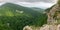 Mountain with a steep rocky slope and valley with thick green forest below