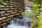 Mountain stream with artificial waterfalls and wooden logs crib wall