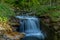 A mountain stream flowing through a landscape in a dense forest captured by long exposure time