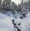 Mountain stream in winter forest covered with snow