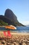 Mountain Sugarloaf sun umbrella and chairs on red beach (Praia