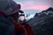 mountain tourist with smartphone taking a picture of a glacier peaks at sunset