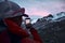 mountain tourist with smartphone taking a picture of a glacier peaks at sunset