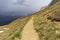 Mountain trail in the Dolomites against the backdrop of an approaching storm