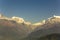 Mountain valley with green wooded slopes and snowy peaks of Annapurna under a clear blue sky