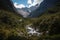 mountain valley, with rushing stream and hidden waterfalls, surrounded by towering mountains