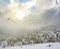 Mountain valley in a snow with sun pushing through  clouds