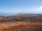 Mountain valley with white buildings and villages between old volcanic slopes. Red Earth and green fields