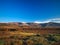 Mountain valley with white buildings and villages between old volcanic slopes. Red Earth and green fields on deep blue sky