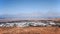 Mountain valley with white buildings and villages between old volcanic slopes. Red Earth and green fields on deep blue sky