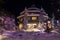 Mountain village after snowfall in night. Christmas illumination - trees, garlands and night lights, snow-covered houses, pine tre