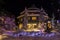 Mountain village after snowfall in night. Christmas illumination - trees, garlands and night lights, snow-covered houses, pine tre