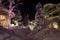 Mountain village after snowfall in night. Christmas illumination - trees, garlands and night lights, snow-covered houses, pine tre