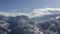 Mountain village on snowy peak on cloudy sky landscape from landing flying drone. Aerial view winding road in snowy mountain resor