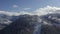 Mountain village on snowy peak on cloudy sky landscape from landing flying drone. Aerial view winding road in snowy mountain resor